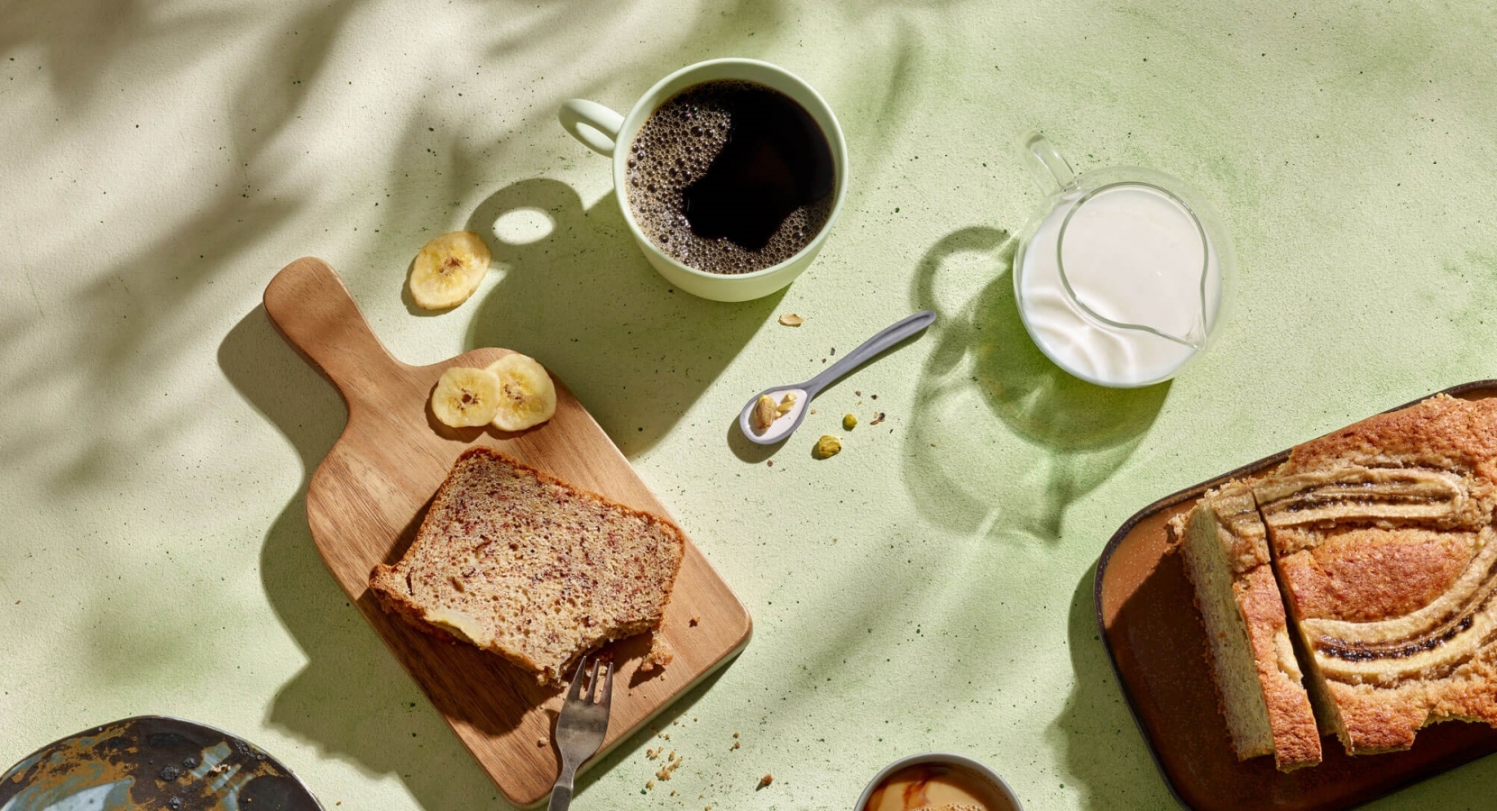 Vegaaninen banaanileipä pöydällä kahvimukien kanssa.
